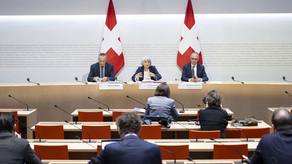 La conseillère fédérale Elisabeth Baume-Schneider est en train de parler entre le directeur de l’Office fédéral des assurances sociales, Stéphane Rossini, à gauche, et le vice-chancelier de la Confédération, Andrea Arcidiacono, à droite, lors d’une conférence de presse au centre de presse du Conseil fédéral, à Berne.