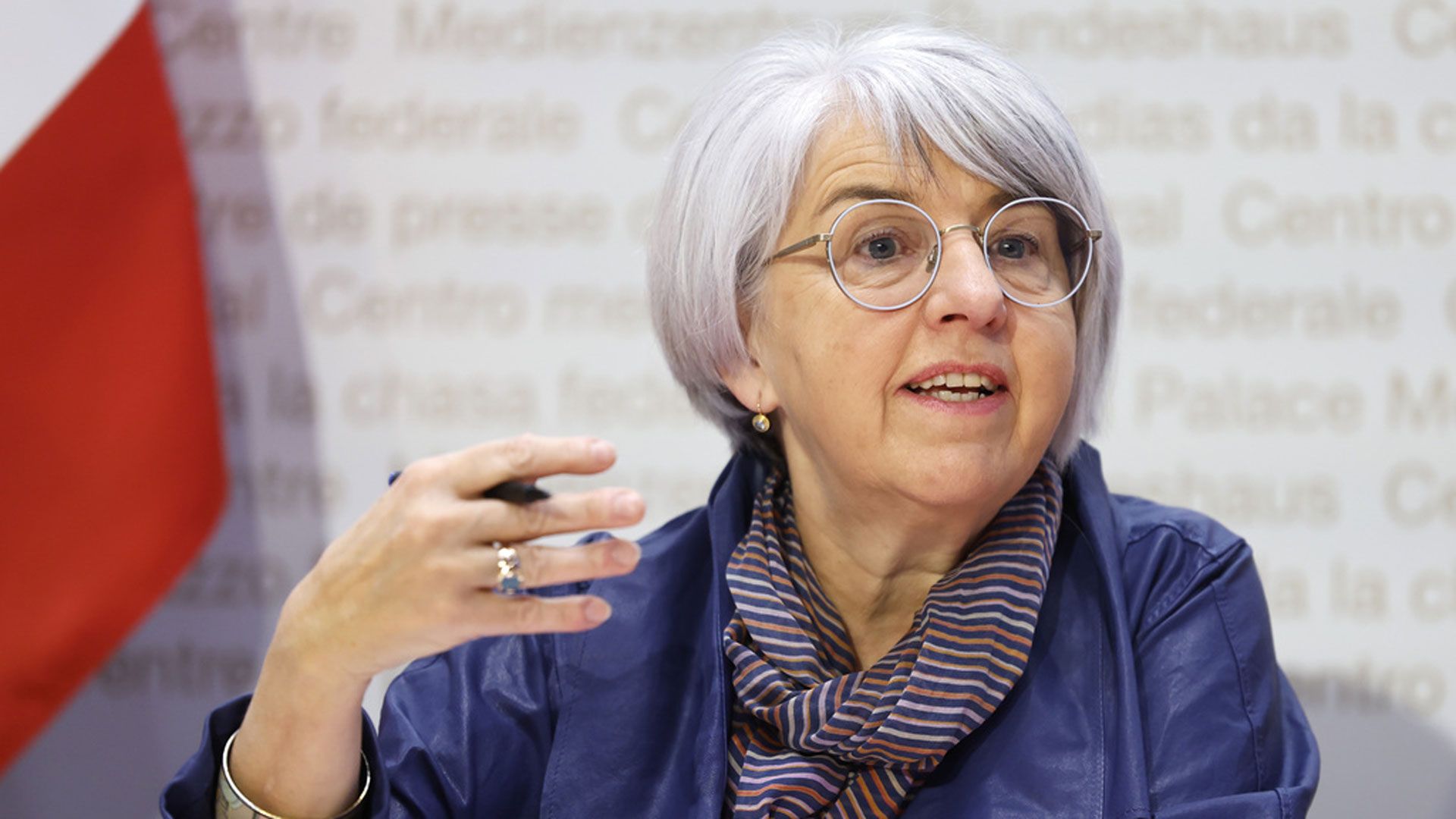 La consigliera federale Elisabeth Baume-Schneider è seduta nel centro media del Consiglio federale, sta parlando e tiene una penna a sfera nella mano destra.
