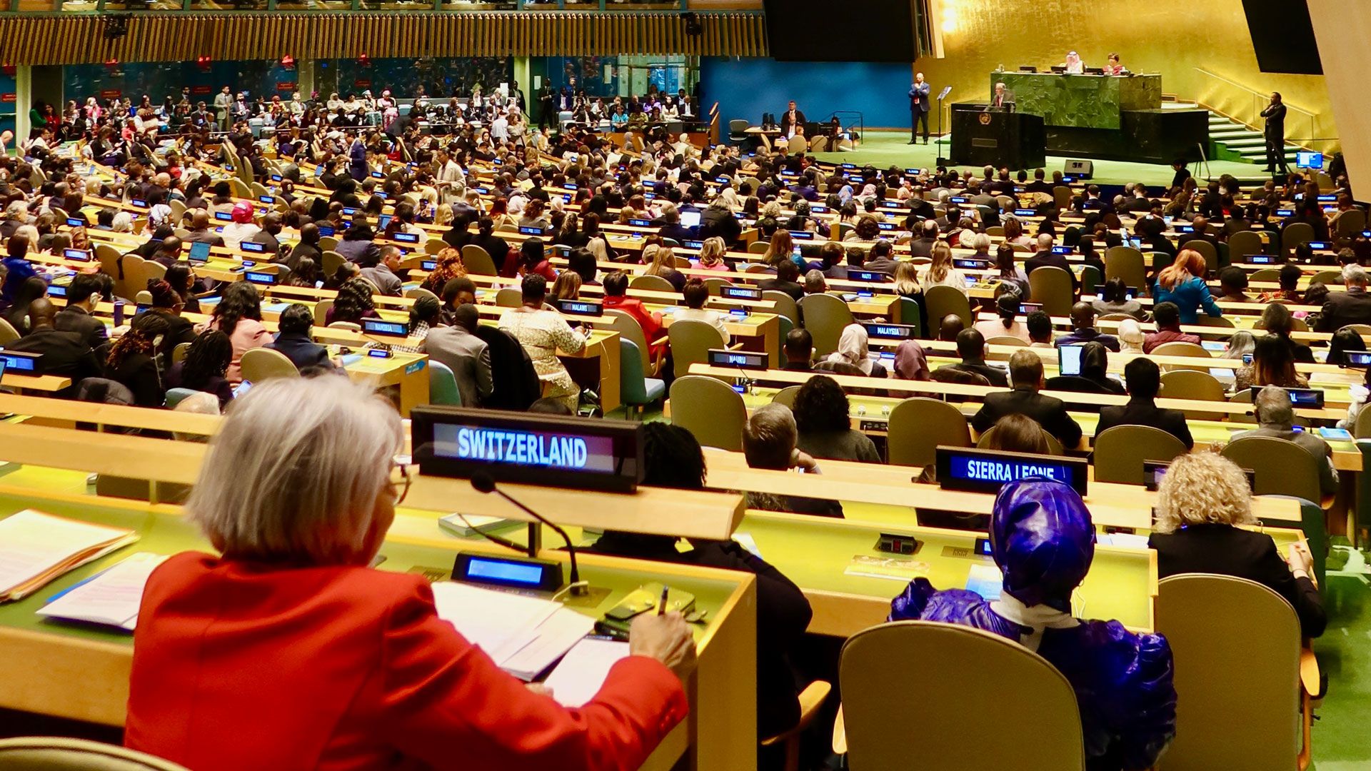 La consigliera federale Elisabeth Baume-Schneider è seduta nella sala dell’Assemblea generale dell’ONU a New York. Davanti a lei c’è un cartellino elettronico con la scritta «Switzerland». Sta ascoltando attentamente e prendendo appunti. La sala è gremita di delegati provenienti da tutto il mondo. In fondo alla sala appare il podio da cui parlano gli oratori durante le sessioni delle Nazioni Unite.